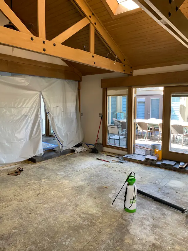 An interior renovation in progress with bare subfloor, protective sheeting and tools in place